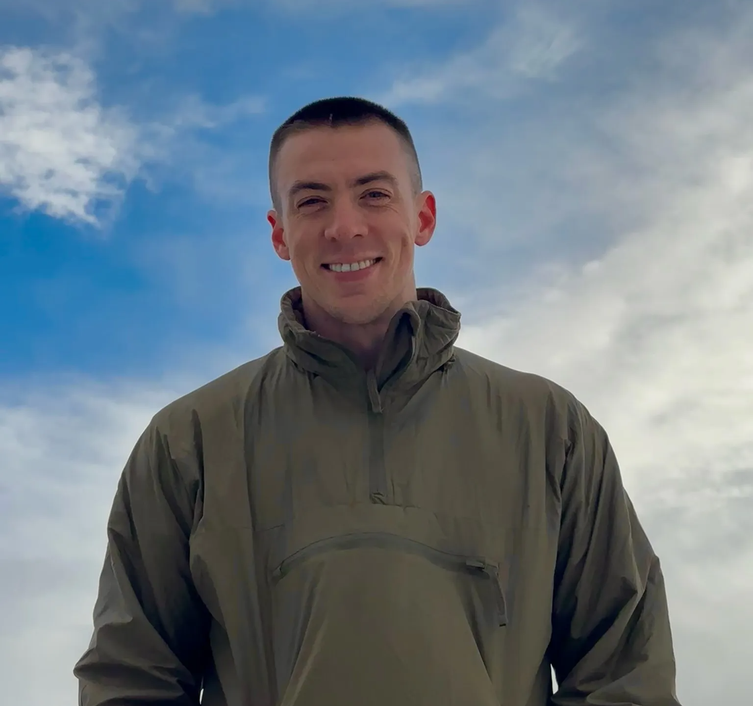 Mark Cunningham, a freelance web developer and digital marketer in Vancouver, standing against a backdrop of blue skies and clouds, wearing an outdoor jacket.